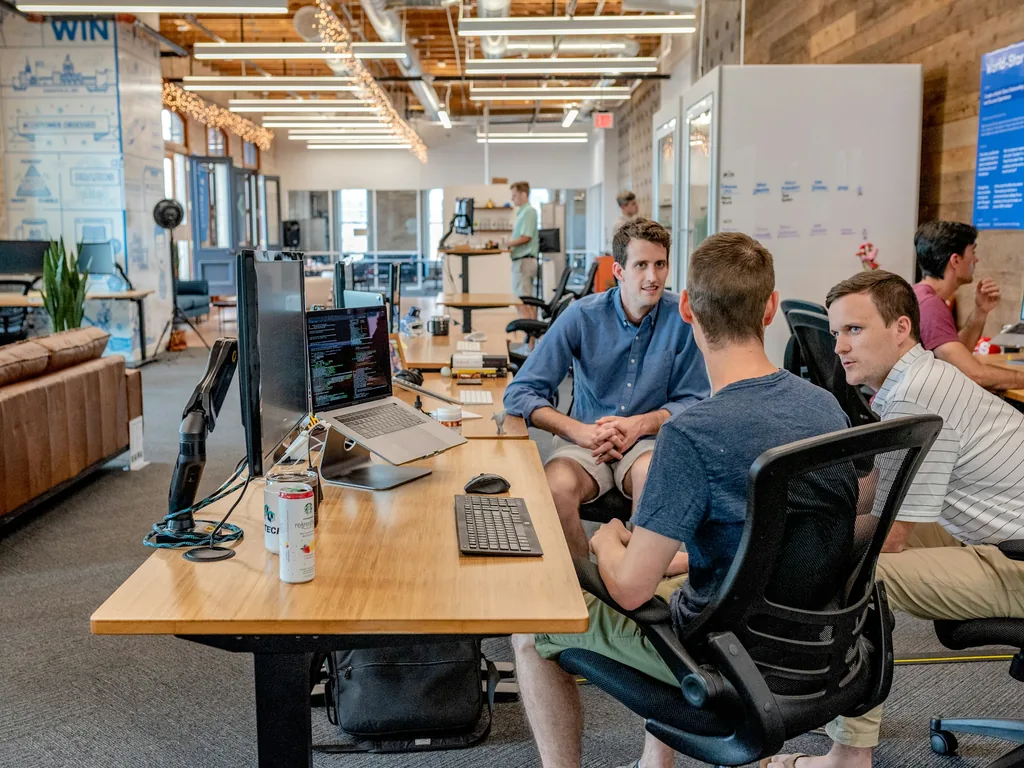 Three men talking at a desk in an office